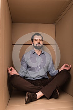 Man meditating in cardboard box