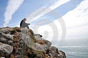 Man meditating on cliff top