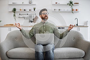 Man meditating on couch during remote work on laptop