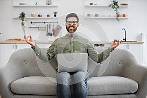 Man meditating on couch during remote work on laptop