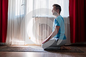 Man meditating on his living room floor sitting. Stay home and be active.