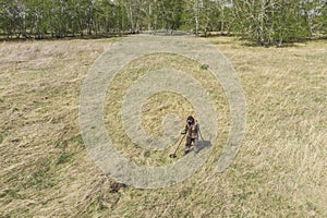 A man with a metal detector on an ancient settlement photographed from a drone