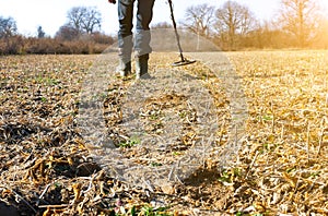 Man with metal detector is moving from side to side on the field for gold and silver metal seeking. Treasure hunt concept