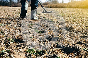 Man with metal detector is moving from side to side on the field for gold and silver metal seeking. Treasure hunt concept