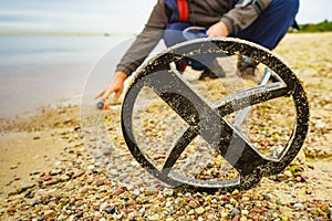 Man with metal detector on sea beach