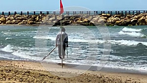 A man with a metal detector searching for some lost money coins or gold jewelry treasure on the beach