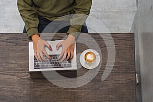 Man in mid green hoodie working on laptop