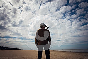 Man in a military gas mask stands on deserted shore against cloudy sky. Human silhouette in a gas mask, side view. Apocalypse