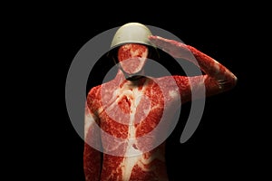 A man in a military helmet. Texture of the meat on the body. Concept - man is just meat in the system. Soldier saluting standing.