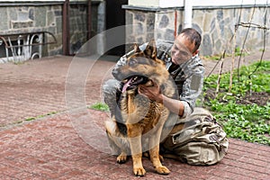 Man in military uniform with German shepherd dog, outdoors.