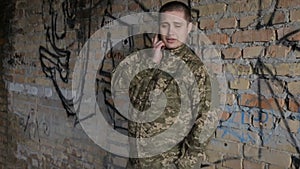 A man in military uniform speaks on the mobile on the ruins