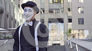 Man mime in hat gesticulate his hands in front of camera