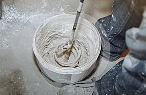 Man is mixing spackling paste putty in the bucket. Grind of wall. Maintenance repair works renovation in the flat. Restoration