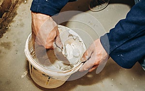 Man is mixing spackling paste putty in the bucket. Grind of wall. Maintenance repair works renovation in the flat. Restoration