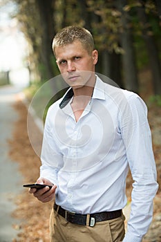 Man with mobile phone in autumn park. Businessman with smartphone outdoor. Blog and weblog in social network. New