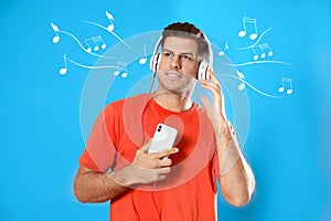 Man with mobile phone listening to music on blue background