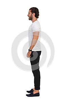 Man In Mocassins, Black Trousers And White T-Shirt Is Standing Relaxed. Side View