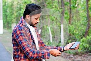 Man model closed  his botton of his shirt with holding a mobile