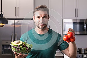 Man in modern kitchen, preparing healthy food alone, cooking salad. Handsome man is preparing fresh vegan salad in the