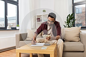 Man with money and calculator filling papers