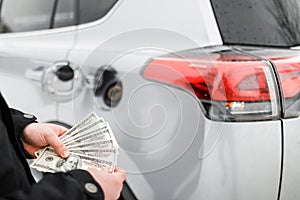 Man with money near car. Money dollars in car fuel tank.