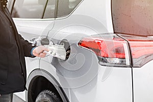 Man with money near car. Money dollars in car fuel tank.