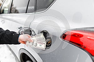 Man with money near car. Money dollars in car fuel tank.