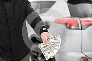 Man with money near car. Money dollars in car fuel tank.