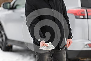 Man with money near car. Money dollars in car fuel tank.