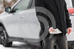 Man with money near car. Money dollars in car fuel tank.