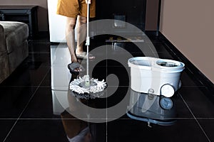 Man mopping floor and mopping bucket on the floor
