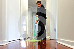 Man mopping a wooden floor at home corridor