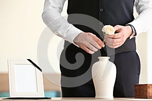 Man with mortuary urn and flower at funeral