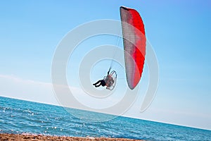 A man on a motor paraglider in the blue sky over the sea, the slope of the horizon. Sports and passion for flying