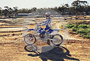 Man, motorbike and outdoor on trail for portrait with helmet on dirt, path and countryside in summer. Person, motorcycle