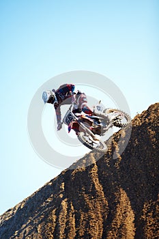 Man, motorcycle and dirt bike on hill professional rider in action danger competition, fearless or race. Male person
