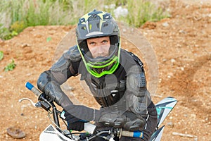 A man in motorcycle equipment sits on an enduro motorcycle