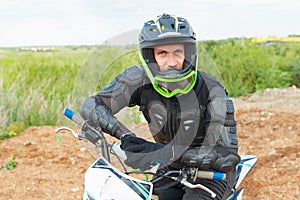 A man in motorcycle equipment sits on an enduro motorcycle photo