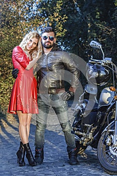 The man on the motorcycle with a young woman in red dress the road