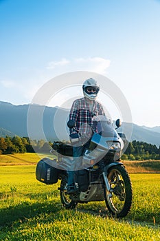 Man motorcyclist ride touring motorcycle in action. Alpine mountains on background. Biker lifestyle, world traveler. Summer sunny