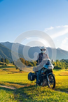 Man motorcyclist ride touring motorcycle in action. Alpine mountains on background. Biker lifestyle, world traveler. Summer sunny