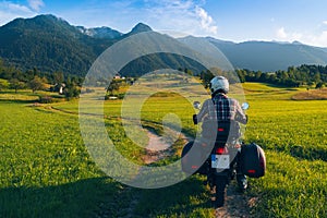 Man motorcyclist ride touring motorcycle. Alpine mountains on background. Biker lifestyle, world traveler. Summer sunny sunset day