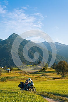 Man motorcyclist ride touring motorcycle. Alpine mountains on background. Biker lifestyle, world traveler. Summer sunny sunset day