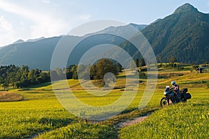 Man motorcyclist ride touring motorcycle. Alpine mountains on background. Biker lifestyle, world traveler. Summer sunny sunset day