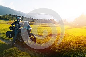 Man motorcyclist ride touring motorcycle. Alpine mountains on background. Biker lifestyle, world traveler. Summer sunny sunset day