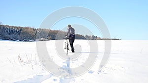 Man with mountain bike on snowy filed. Biker is pushing bike in deep snow. Cloudy winter day with gentle wind and snow flakes