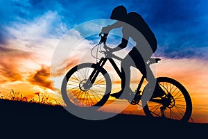 Man on mountain bike at sunset, riding bicycle on hills