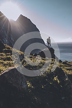 Man mountaineer standing on rock of peak mountain at sunset. Ryten Mountain, Norway