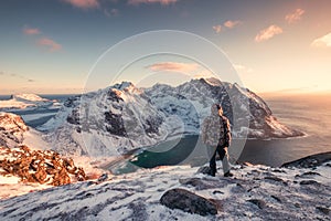 Man mountaineer standing on snowy mountain at sunset