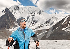 Man mountaineer in sunglasses against blue sky and mountain glacier, adventure concept